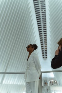 a woman in a white suit standing in front of a building